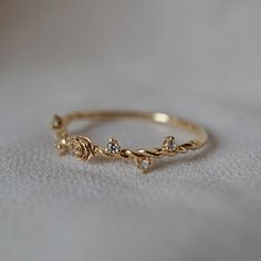 a gold ring with three small diamonds on it's side, sitting on a white surface