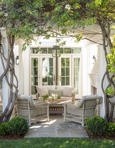 an outdoor living area with wicker furniture and trees in the foreground, surrounded by greenery