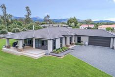 an aerial view of a home in the middle of a green yard with mountains in the background