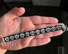 a hand holding a black and white beaded wristband with numbers on it's side