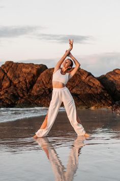 a woman is doing yoga on the beach