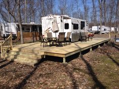 a deck with chairs and an rv parked in the background