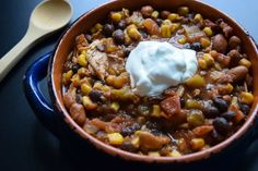 a bowl filled with beans, corn and sour cream on top of a blue table