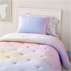 a white bed with pink and blue pillows