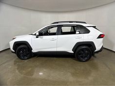 a white toyota rav parked in a room with black rims and dark tires