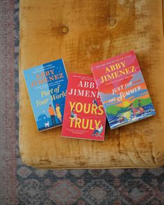 three children's books sitting on top of a yellow chair next to a rug