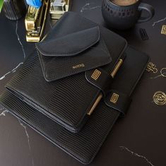 a black leather case sitting on top of a table next to a cup and pen