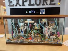 a fish tank filled with lots of different types of sea life in front of a sign that reads explore i spy