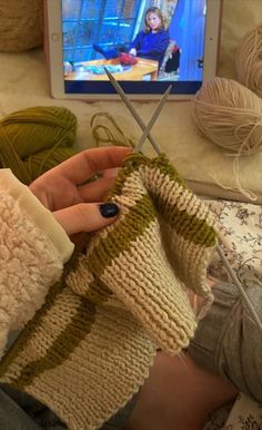 a woman is knitting in front of a television