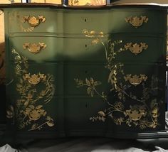 a green dresser with gold leaf designs on it