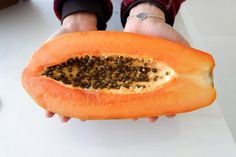 a person holding a half eaten papaya fruit in their hands with seeds on it