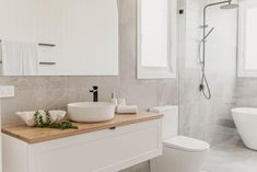 a bathroom with a sink, toilet and bathtub in the background is an open shower