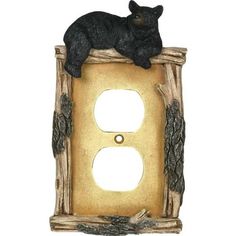 a black bear sitting on top of a light switch cover in a tree stump frame