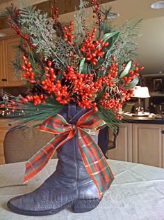 a boot with red berries and greenery tied to it sits on a table in front of a kitchen