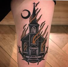 a tattoo on the leg of a person with a church and flames around it,