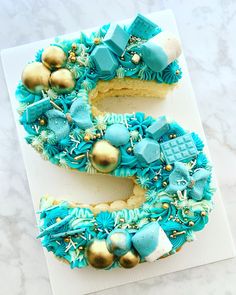 the letter e is made out of cake and decorated with blue icing, gold decorations