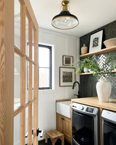 a washer and dryer in a small room with open shelves on the wall