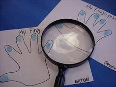 a magnifying glass sitting on top of paper with handprints under it