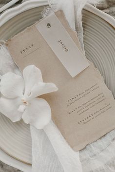 a white flower sitting on top of a plate next to a piece of parchment paper