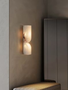 a wall light that is on the side of a wall next to a bench in a room