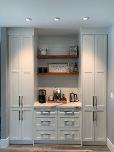 a kitchen with gray cabinets and white counter tops, coffee maker on the far wall