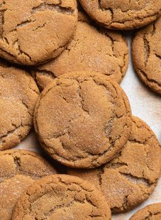 a pile of brown cookies sitting on top of a white tablecloth covered in powdered sugar