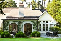 a white house with ivy growing on it's walls and patio furniture in the foreground