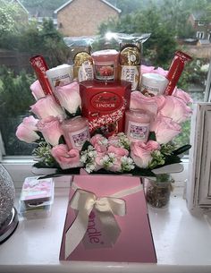 a bouquet of pink roses and chocolates in a gift box on a window sill