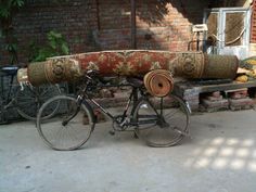 an old bicycle is loaded with rugs and other things to sell on the street