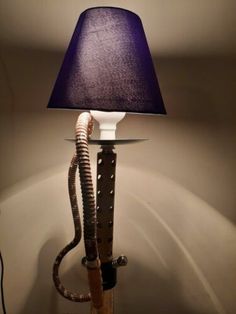 a lamp that is on top of a table with a snake wrapped around it's base