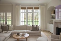 a living room filled with furniture and a fire place in front of a large window