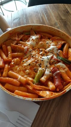 a pan filled with pasta and vegetables on top of a wooden table