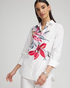 a woman wearing white pants and a shirt with flowers on it