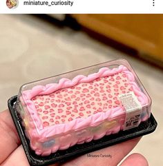 someone is holding a cake shaped like a box with pink frosting and hearts on it