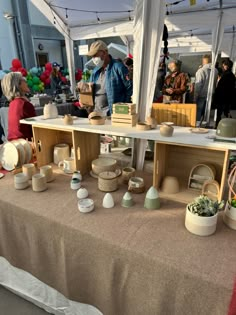 an outdoor market with people shopping and selling items on the tables in front of them