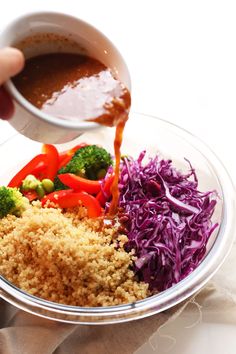 someone is pouring sauce on some food in a bowl with broccoli and red cabbage