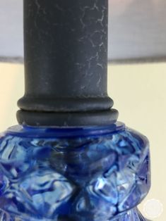 a blue glass table lamp sitting on top of a white table