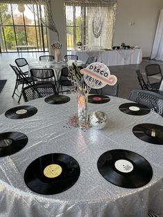 a table topped with black and white plates covered in vinyl record records next to a vase filled with flowers