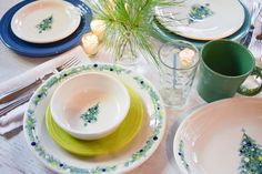 the table is set with plates, cups and utensils for christmas dinner party