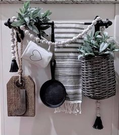 kitchen utensils hanging on the wall with potted plants and other things in them