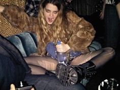 a woman sitting on top of a blue couch holding a bottle and wearing tights