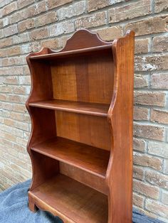 a wooden book shelf sitting against a brick wall