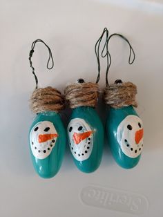 three snowman ornaments hanging from twine