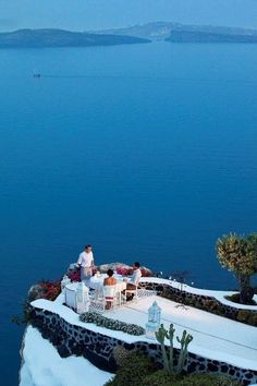 two people sitting at an outdoor table overlooking the ocean