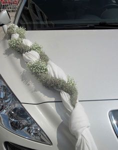 a white car decorated with flowers and greenery