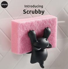 a pink sponge with a black cat figurine hanging from it's side