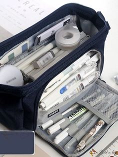 an open travel bag filled with pens, markers and pencils on top of a desk