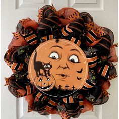 a halloween mesh wreath with an image of a pumpkin and a cat on the front door