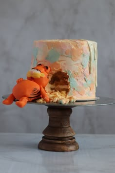 a cake with frosting and icing that looks like an orange bird on top