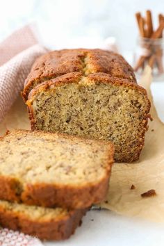 a loaf of banana bread sitting on top of a cutting board next to some cinnamon sticks